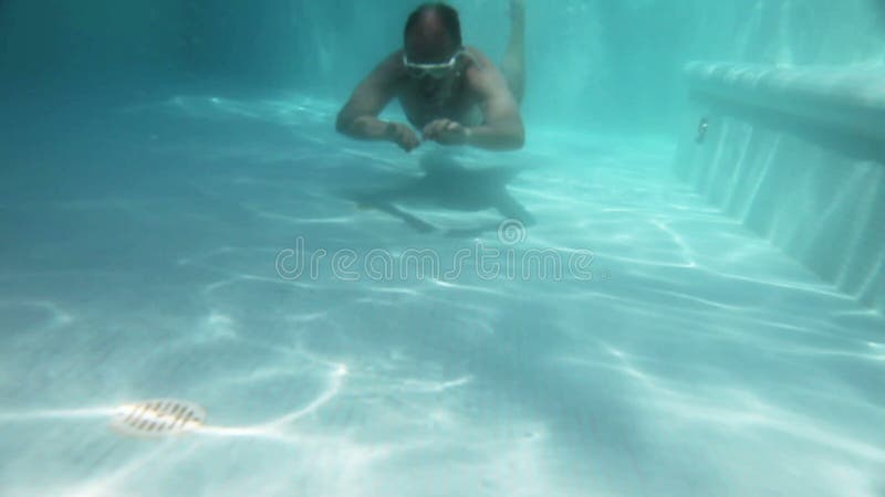 L'uomo nuota sotto l'acqua nello stagno