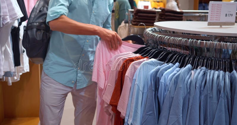 L'uomo prende una maglietta rosa dal display piace. impugnazione di assortimento. assortimento parte camicia. scelta preferisci mo