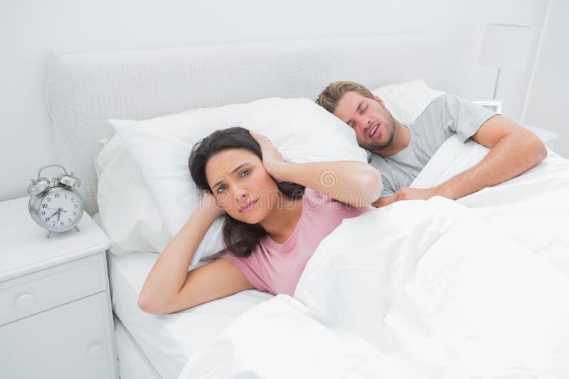 L'uomo russante sta infastidendo la sua moglie che prova a dormire fotografia stock L'uomo russante sta infastidendo la sua moglie che prova a dormire fotografia stock