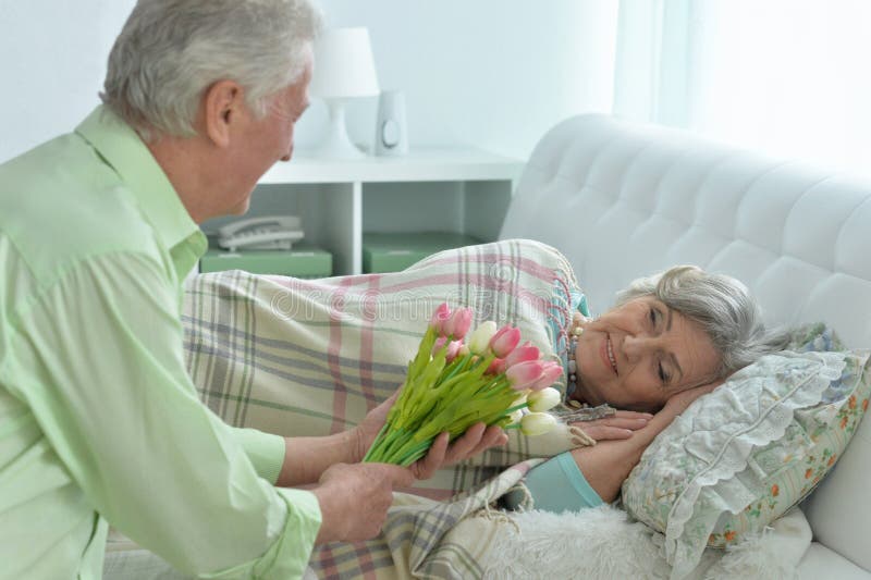L'uomo senior dà i fiori ad una donna fotografie stock L'uomo senior dà i fiori ad una donna fotografie stock