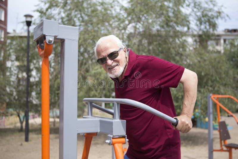 L'uomo senior si prepara su attrezzatura di sport su aria aperta immagine stock L'uomo senior si prepara su attrezzatura di sport su aria aperta immagine stock