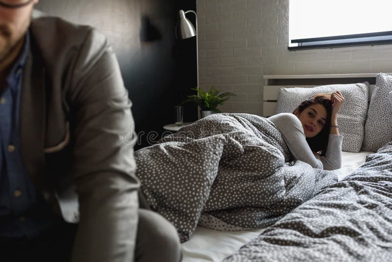 L'uomo sta andando lavorare di mattina lasciando una donna nel letto immagine stock L'uomo sta andando lavorare di mattina lasciando una donna nel letto immagine stock