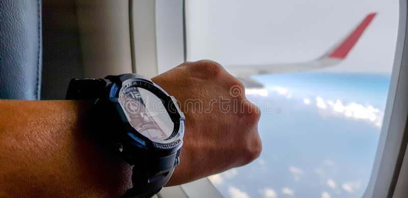 L'uomo sull'æreo a reazione è nella situazione della fretta in modo che fissi sempre al suo orologio immagine stock L'uomo sull'æreo a reazione è nella situazione della fretta in modo che fissi sempre al suo orologio immagine stock