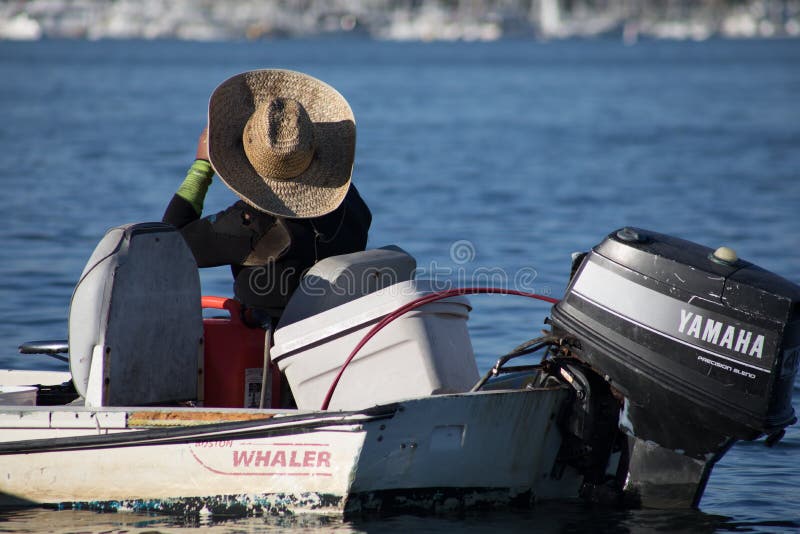 L'uomo in un grande cappello di paglia si siede in suo crogiolo di baleniere di Boston alla e fotografia stock libera da diritti L'uomo in un grande cappello di paglia si siede in suo crogiolo di baleniere di Boston alla e fotografia stock libera da diritti