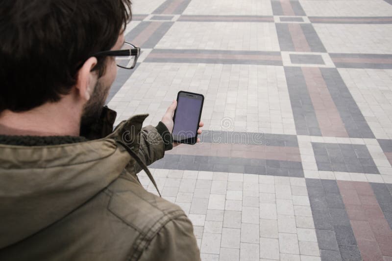 L'uomo utilizza il suo telefono cellulare all'aperto, alto vicino fotografia stock L'uomo utilizza il suo telefono cellulare all'aperto, alto vicino fotografia stock