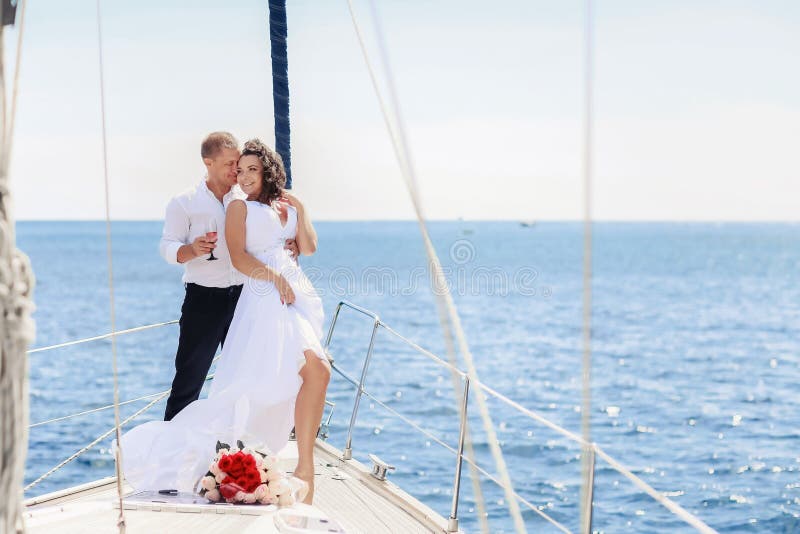 White yacht with sail set goes along the island on a hot day. blue sea, blue sky. Crimea. on board a young couple in love. the bride and groom. wedding boat trip. White yacht with sail set goes along the island on a hot day. blue sea, blue sky. Crimea. on board a young couple in love. the bride and groom. wedding boat trip.