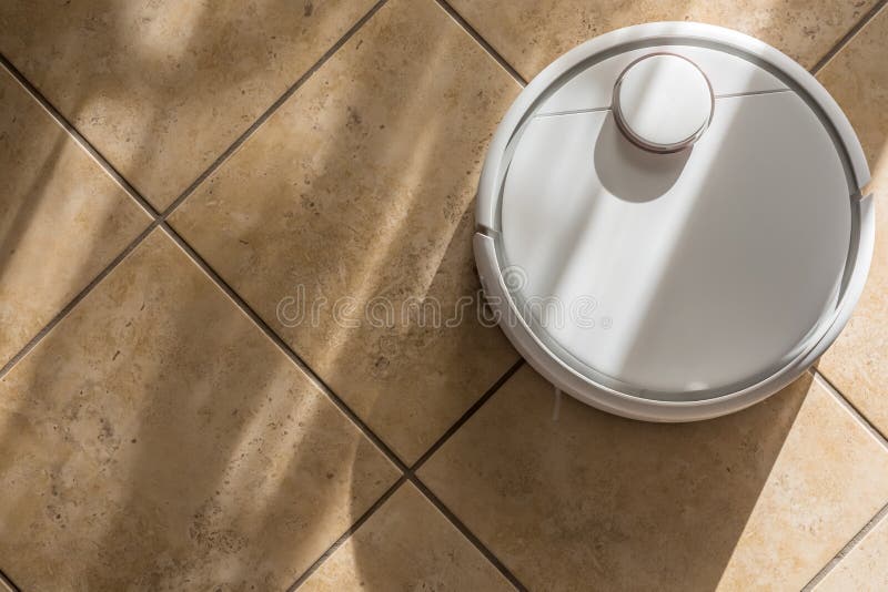 L'épargne de temps dans le ménage par le soin de plancher avec un robot intelligent de vide photo stock L'épargne de temps dans le ménage par le soin de plancher avec un robot intelligent de vide photo stock