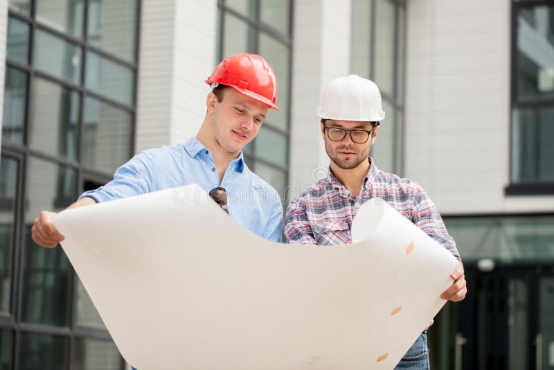 L'équipe de constructeurs travaillent accordant le plan et le plan photographie stock libre de droits L'équipe de constructeurs travaillent accordant le plan et le plan photographie stock libre de droits