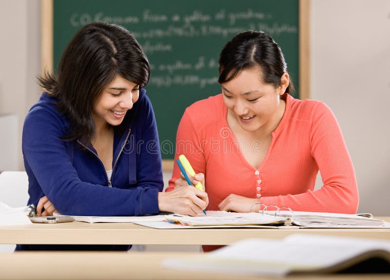 Determined student with text books helping friend do homework in school classroom. Determined student with text books helping friend do homework in school classroom
