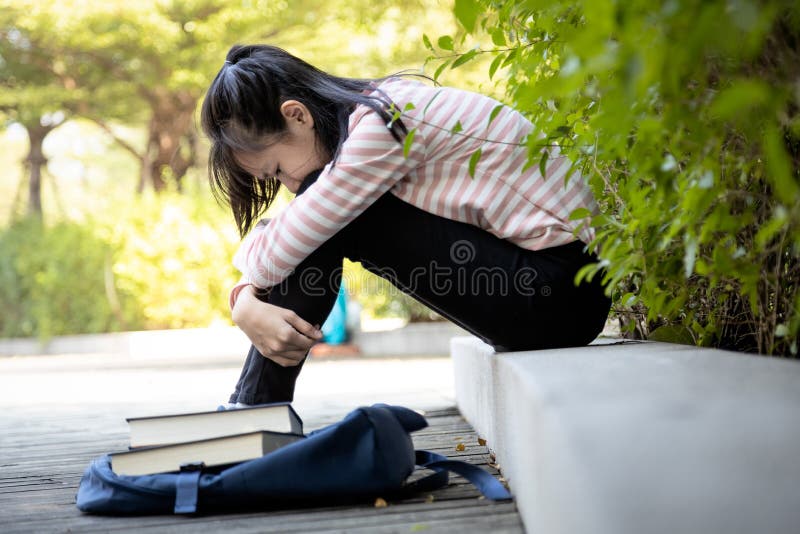 Depressed asian child girl student failed important test,female student sit hugs her knees up to the chest and crying alone,sad schoolgirl feel stressed,disappointed with her exam at primary school. Depressed asian child girl student failed important test,female student sit hugs her knees up to the chest and crying alone,sad schoolgirl feel stressed,disappointed with her exam at primary school