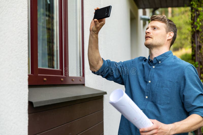 Male real estate appraiser taking pictures of property with phone. Male real estate appraiser taking pictures of property with phone