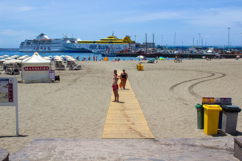 La bahía en y la terminal de transbordadores arenosas en Los Cristianos en Tenerife con la isla balsea en los fabricantes del pue foto de archivo La bahía en y la terminal de transbordadores arenosas en Los Cristianos en Tenerife con la isla balsea en los fabricantes del pue foto de archivo