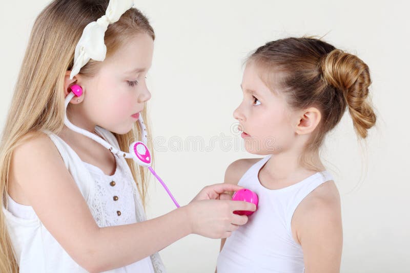 La bambina ascolta battito cardiaco di un'altra ragazza dal phonendoscope del giocattolo