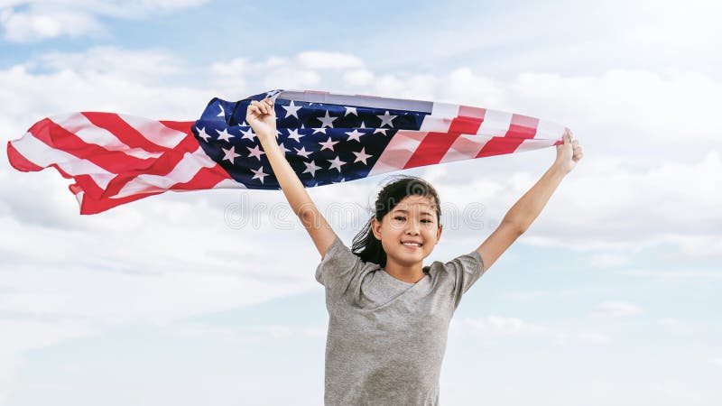 La bambina asiatica felice con la bandiera americana U.S.A. celebra il quarto luglio fotografia stock libera da diritti La bambina asiatica felice con la bandiera americana U.S.A. celebra il quarto luglio fotografia stock libera da diritti