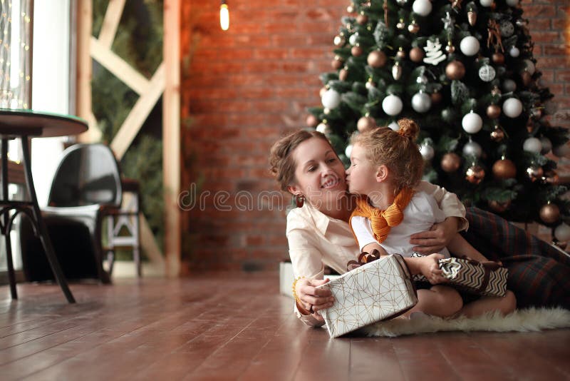 La bambina bacia sua madre vicino all'albero di Natale fotografia stock libera da diritti La bambina bacia sua madre vicino all'albero di Natale fotografia stock libera da diritti