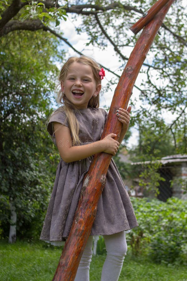 La bambina che ride abbracciando un albero, bella ragazza bionda abbraccia un albero e sorridere fotografia stock libera da diritti La bambina che ride abbracciando un albero, bella ragazza bionda abbraccia un albero e sorridere fotografia stock libera da diritti