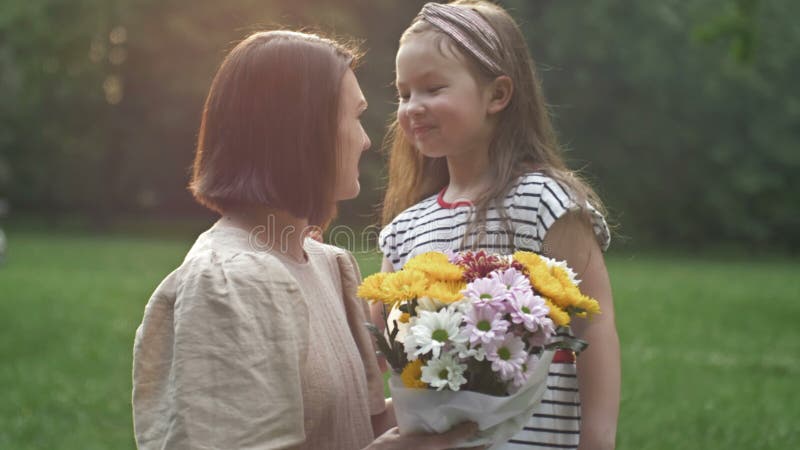 La bambina dà dei fiori a sua madre. bella famiglia insieme. giornata estiva. ritratto familiare. felice maternità. godere