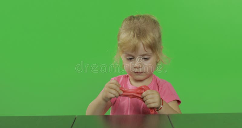 La bambina felice gioca con plasticine sul fondo chiave dell'intensità fotografie stock libere da diritti La bambina felice gioca con plasticine sul fondo chiave dell'intensità fotografie stock libere da diritti