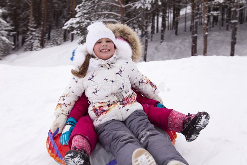 La bambina felice grida con delizia, rotolante con la collina della neve fotografia stock La bambina felice grida con delizia, rotolante con la collina della neve fotografia stock