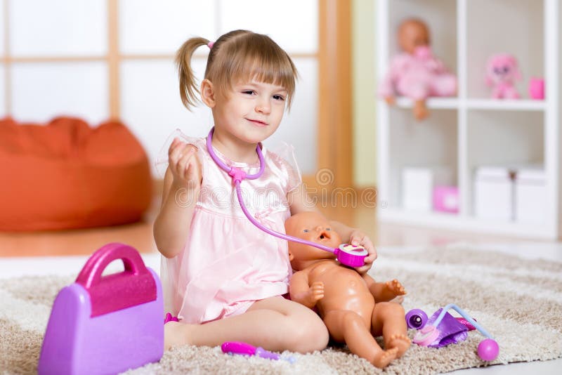 La bambina gioca al dottore esaminando un paziente della bambola fotografia stock libera da diritti La bambina gioca al dottore esaminando un paziente della bambola fotografia stock libera da diritti