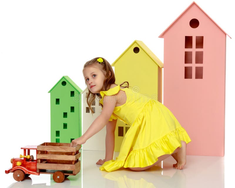 La bambina sta giocando con un'automobile di legno Il concetto di un'infanzia felice, giocando in un asilo ed in una famiglia Isolato su priorità bassa bianca