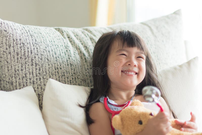 La bambina sveglia asiatica è sorridente e giocante al dottore con lo stetho fotografie stock La bambina sveglia asiatica è sorridente e giocante al dottore con lo stetho fotografie stock