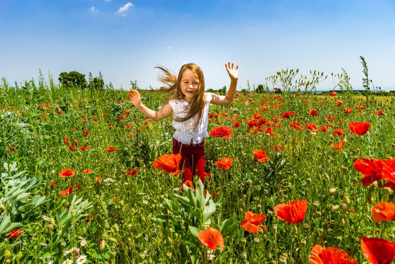 La bambina sveglia che gioca nei papaveri rossi sistema il giorno di estate, bellezza fotografia stock La bambina sveglia che gioca nei papaveri rossi sistema il giorno di estate, bellezza fotografia stock
