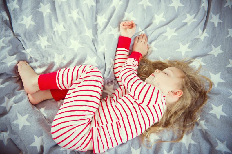 La bambina sveglia dorme nei pajames sul letto fotografia stock libera da diritti La bambina sveglia dorme nei pajames sul letto fotografia stock libera da diritti