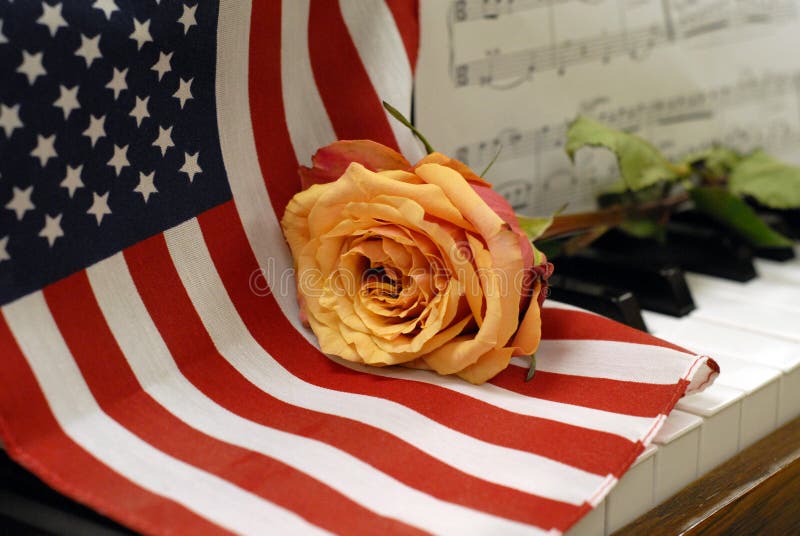La bandiera americana sulle chiavi del piano con la rosa dorata e la musica segnano immagini stock La bandiera americana sulle chiavi del piano con la rosa dorata e la musica segnano immagini stock
