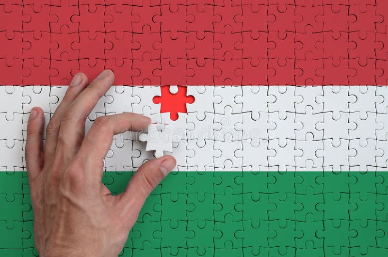 La bandiera dell'Ungheria è descritta su un puzzle, che la mano del ` s dell'uomo completa per piegare