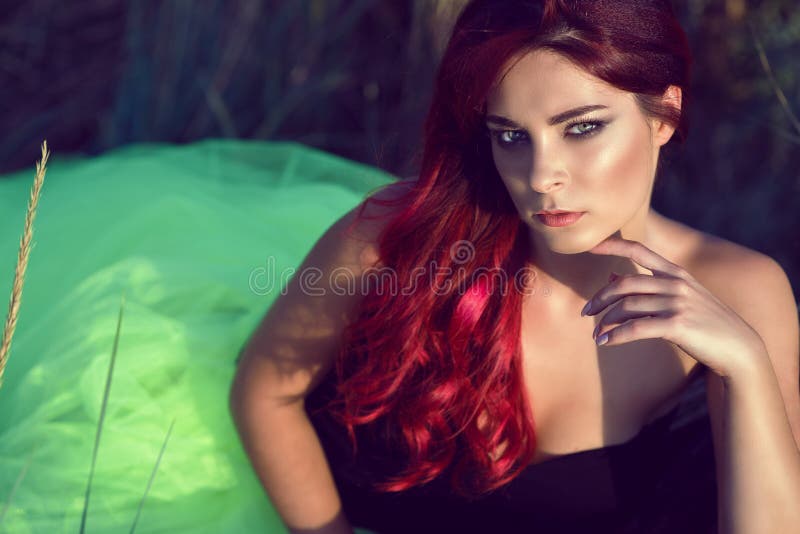 La beaux femme avec les cheveux rouges lumineux et provocateurs composent la jupe voilante pelucheuse de port se reposant dans le photos stock La beaux femme avec les cheveux rouges lumineux et provocateurs composent la jupe voilante pelucheuse de port se reposant dans le photos stock