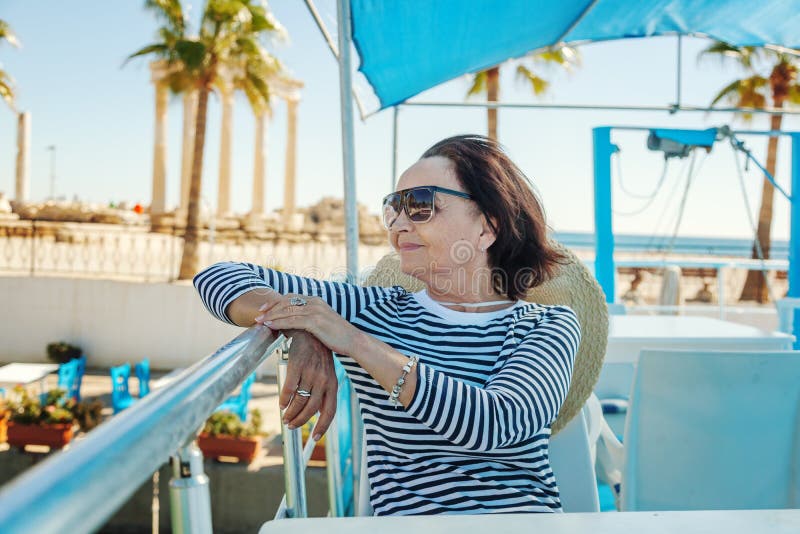La bella donna anziana alla moda viaggia su un yacht, su un backgro immagine stock libera da diritti La bella donna anziana alla moda viaggia su un yacht, su un backgro immagine stock libera da diritti