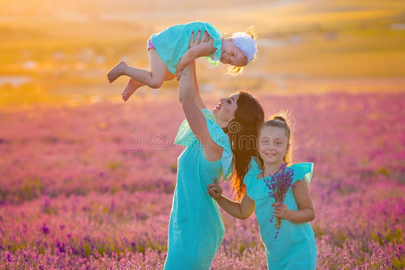 La bella famiglia delle ragazze sveglie gode della vita con il prato del tramonto di potere della ragazza sopra di lavanda Mamma immagine stock La bella famiglia delle ragazze sveglie gode della vita con il prato del tramonto di potere della ragazza sopra di lavanda Mamma immagine stock