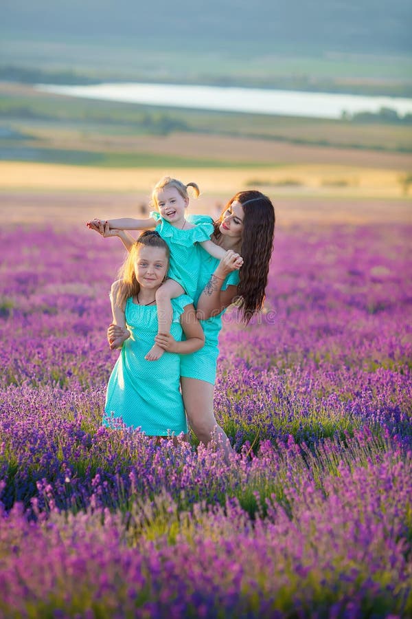 La bella famiglia delle ragazze sveglie gode della vita con il prato del tramonto di potere della ragazza sopra di lavanda Mamma fotografia stock libera da diritti La bella famiglia delle ragazze sveglie gode della vita con il prato del tramonto di potere della ragazza sopra di lavanda Mamma fotografia stock libera da diritti