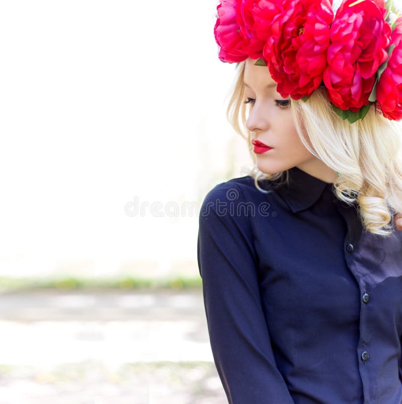 La bella giovane giovane donna bionda elegante delicata con una corona rossa della peonia in una blusa nera cammina nel meleto fe immagini stock La bella giovane giovane donna bionda elegante delicata con una corona rossa della peonia in una blusa nera cammina nel meleto fe immagini stock