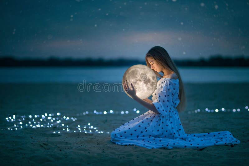 La bella ragazza attraente su una spiaggia di notte con la sabbia e le stelle abbraccia la luna, fotografia artistica