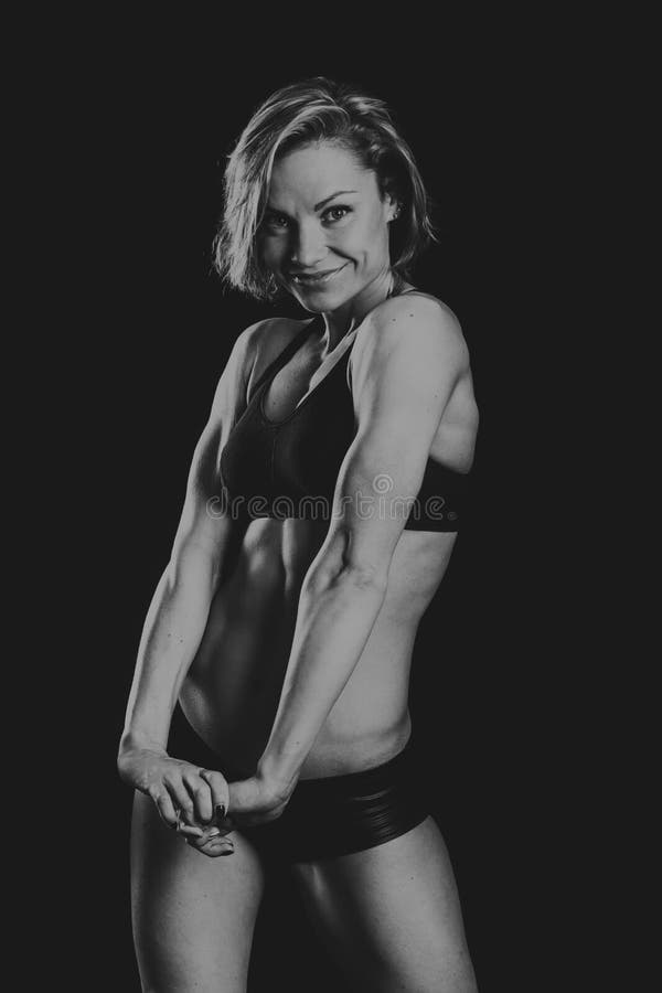 La bella ragazza di sport su un fondo scuro fotografie stock libere da diritti La bella ragazza di sport su un fondo scuro fotografie stock libere da diritti