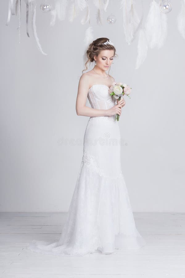 La bella sposa con pizzo fiorisce in suoi capelli biondi scuri splendidi Alti acconciatura, trecce e riccioli di nozze immagine stock libera da diritti La bella sposa con pizzo fiorisce in suoi capelli biondi scuri splendidi Alti acconciatura, trecce e riccioli di nozze immagine stock libera da diritti