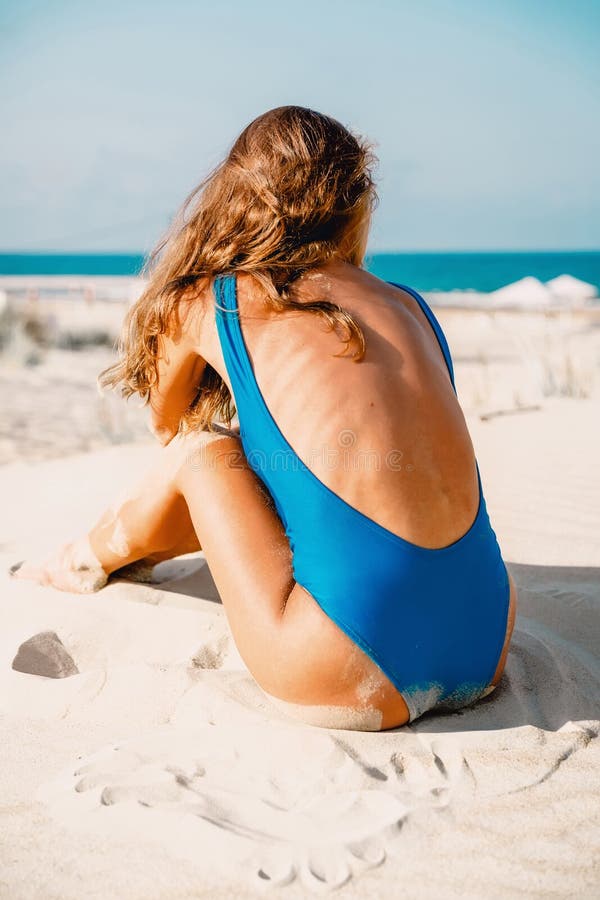 La belle femme dans le bikini bleu s'asseyent sur la plage tropicale Corps de femme d'été photo stock La belle femme dans le bikini bleu s'asseyent sur la plage tropicale Corps de femme d'été photo stock