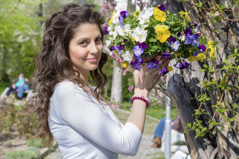 La belle femme de brune souriant et tenant un panier de ressort fleurit photos stock La belle femme de brune souriant et tenant un panier de ressort fleurit photos stock