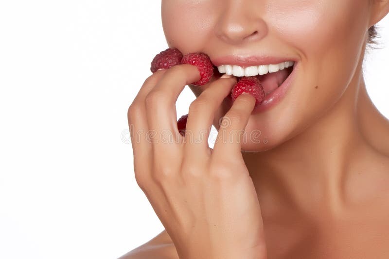 La belle femme sexy de brune tenant quatre baies sur ses doigts, sourire sexy et va manger des framboises sur un backgro blanc photographie stock La belle femme sexy de brune tenant quatre baies sur ses doigts, sourire sexy et va manger des framboises sur un backgro blanc photographie stock