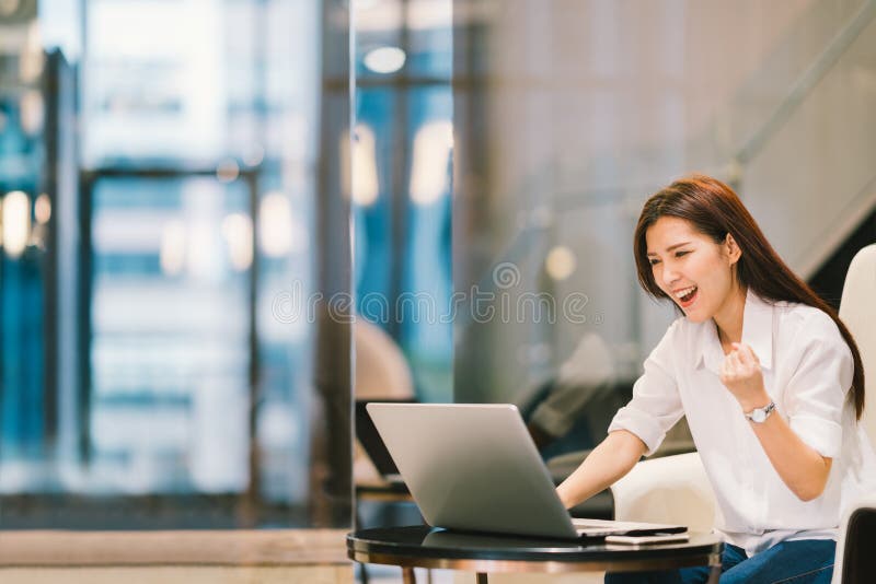 La belle fille asiatique célèbrent avec l'ordinateur portable, la pose de succès, l'éducation ou la technologie ou le concept de photos libres de droits