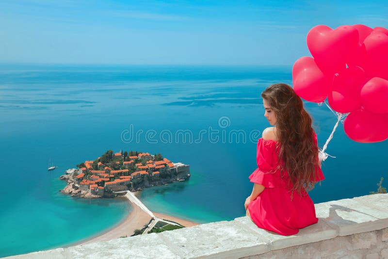 La belle fille avec le coeur monte en ballon au-dessus de l'île de Sveti Stefan à B