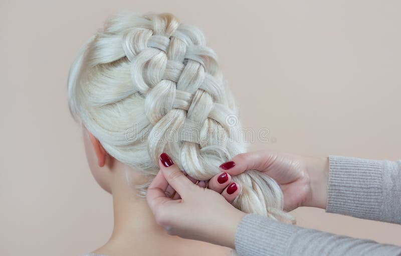 La belle fille avec les cheveux blonds, coiffeuse tisse un plan rapproché de tresse, dans un salon de beauté image libre de droits La belle fille avec les cheveux blonds, coiffeuse tisse un plan rapproché de tresse, dans un salon de beauté image libre de droits