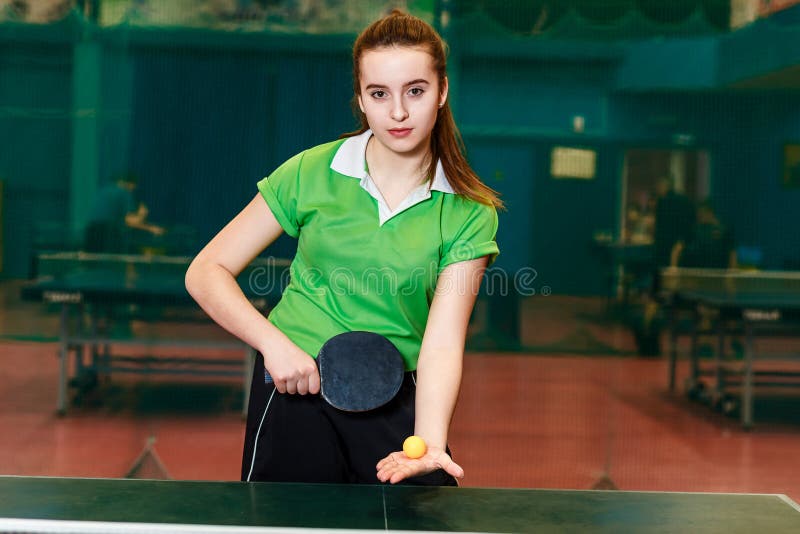 La belle fille de l'adolescence de couleur claire dans les sports forment tenir une boule et une raquette pour le ping-pong photos stock La belle fille de l'adolescence de couleur claire dans les sports forment tenir une boule et une raquette pour le ping-pong photos stock