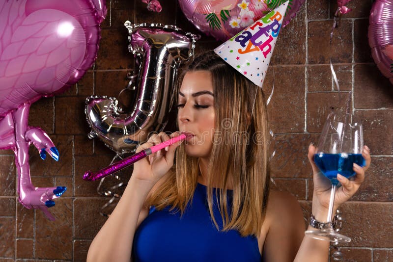 La belle fille heureuse avec les éruptions musicales et la lagune bleue de cocktail à disposition et le chapeau sur la tête célèb images stock La belle fille heureuse avec les éruptions musicales et la lagune bleue de cocktail à disposition et le chapeau sur la tête célèb images stock