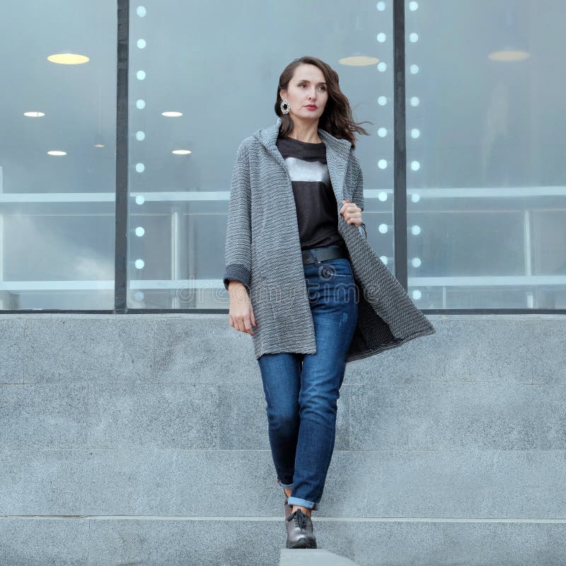 La belle fille marche par la ville La brune ?l?gante dans un manteau et des jeans avance Printemps ou automne Demi de la publicit photo libre de droits La belle fille marche par la ville La brune ?l?gante dans un manteau et des jeans avance Printemps ou automne Demi de la publicit photo libre de droits