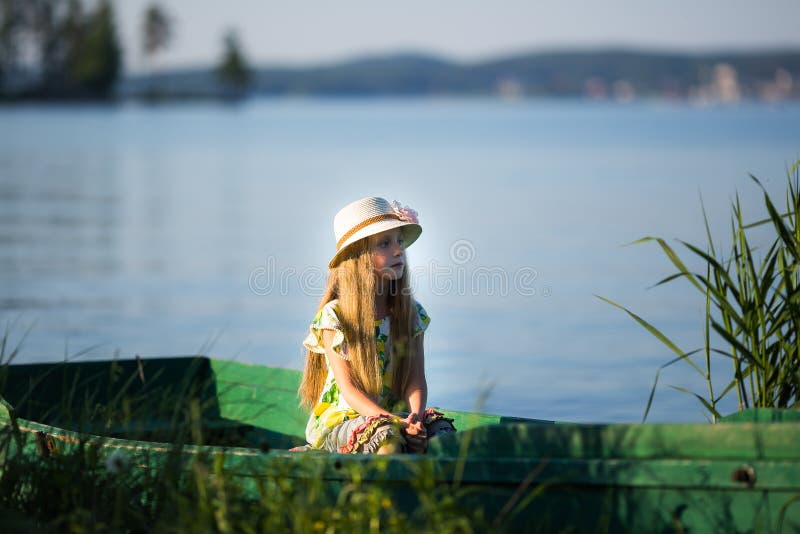 La belle fille mignonne s'assied dans un bateau sur le lac photo stock La belle fille mignonne s'assied dans un bateau sur le lac photo stock