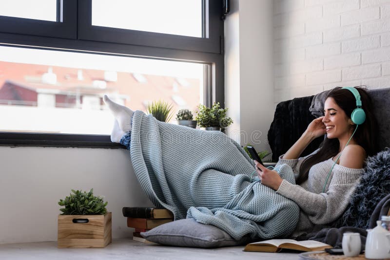 La belle jeune femme apprécie à la maison la musique de écoute image stock La belle jeune femme apprécie à la maison la musique de écoute image stock