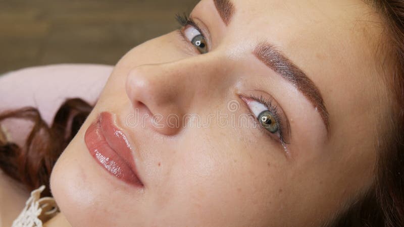 La belle jeune femme avec le maquillage permanent de la lèvre et le tatouage microblading de sourcil se retrouve avec un salon de clips vidéos